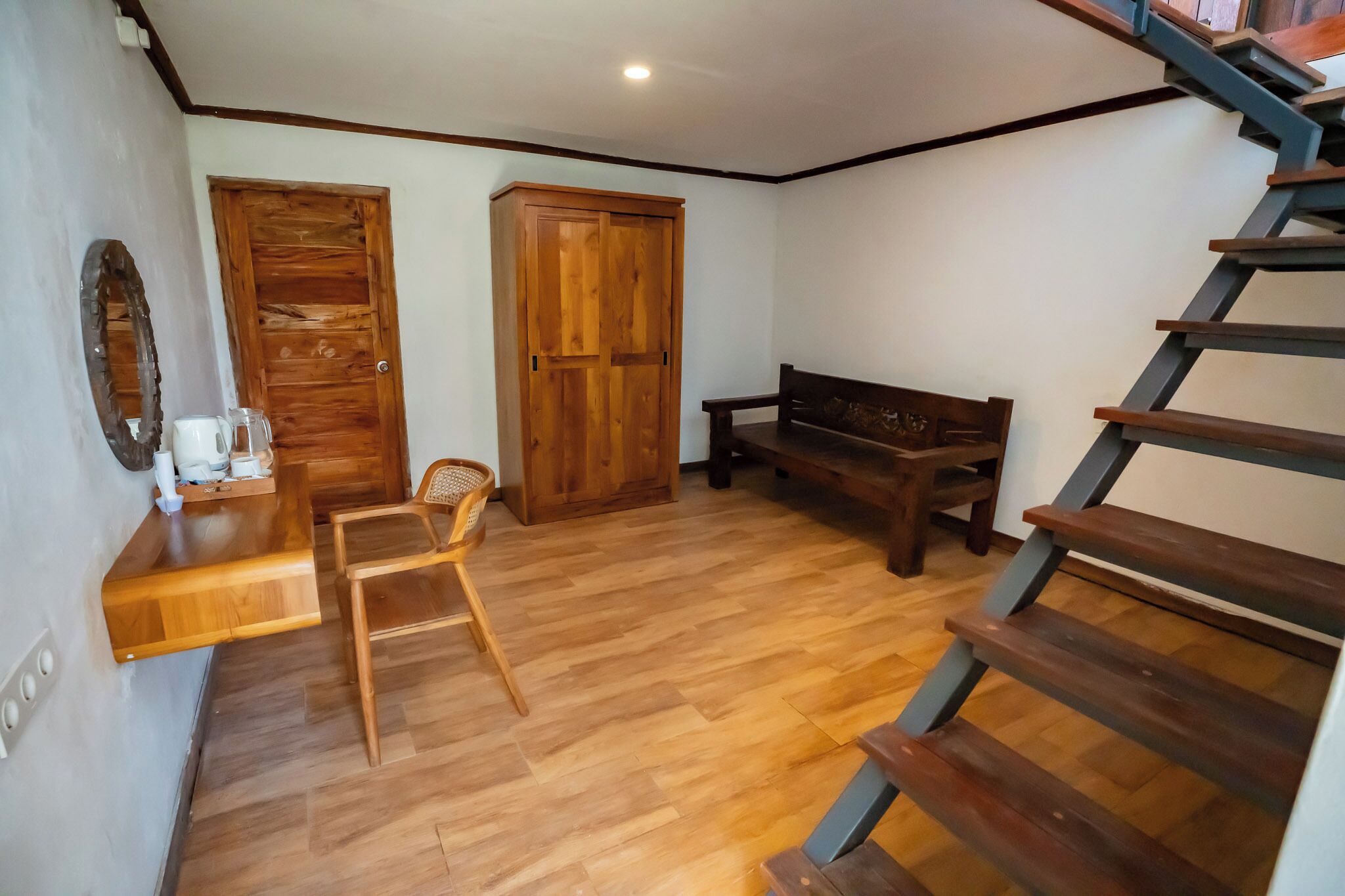 A room with a wooden floor, a wooden bench, a wooden staircase, and a wooden door.