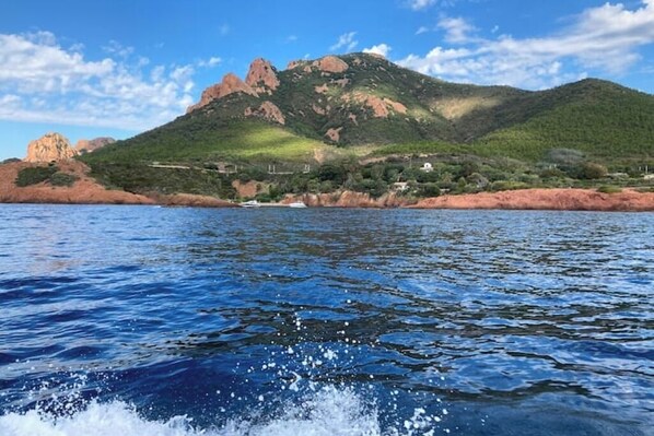 Un paisaje costero con una montaña, una masa de agua y algunos edificios.