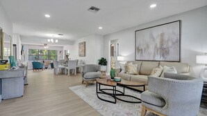 A spacious living room with a sofa, armchairs, and a coffee table. There is a dining area in the background with a table and chairs. - Dania Beach 4BR • Pool • Game Room • Discounted! (Dania Beach)