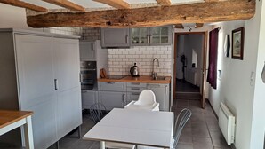 Una cocina compacta con gabinetes grises, una encimera de madera y una mesa blanca.