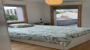 A bedroom with a bed, a window, a door, and a ceiling light.