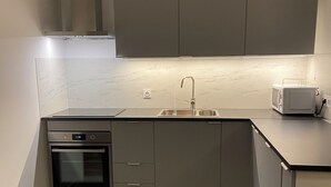 A compact kitchen with a built-in oven, a microwave, and a sink.
