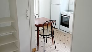 A small, clean kitchen with white appliances, a wooden table, and a chair. - Vacation studio in private house. (Concarneau)
