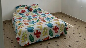 A bedroom with a bed, two windows with curtains, and a tiled floor. - Vacation studio in private house. (Concarneau)