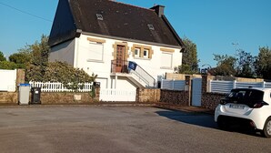 A two-story house with a white exterior, a dark roof, and a small balcony. - Vacation studio in private house. (Concarneau)