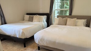 Ein Schlafzimmer mit zwei Betten, einem großen Fenster und Holzboden.