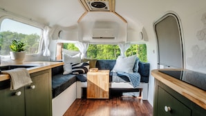 Een compact interieur van een camper, met een kitchenette, zithoek en een klein tafeltje.
