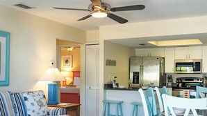 A compact living space with a kitchenette, a dining area with mismatched chairs, and a sofa with striped cushions. - Foxtail Palm: Steps from the beach (Holmes Beach)