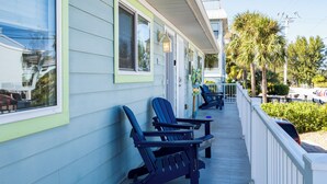 A motel with a covered porch, outdoor seating, and a view of the street. - Foxtail Palm: Steps from the beach (Holmes Beach)