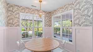 A dining room with a round wooden table, clear chairs, and a chandelier. - The Salty Flamingo w Pool+Hot Tub+Ping Pong (Murrayville)