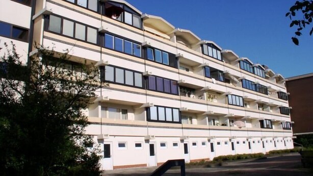 Ein mehrstöckiges Hotel mit Balkonen, großen Fenstern und einer flachen Dachfläche.
