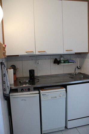 A compact kitchen with white cabinets, a small countertop, a coffee maker, a mini fridge, and a dishwasher.