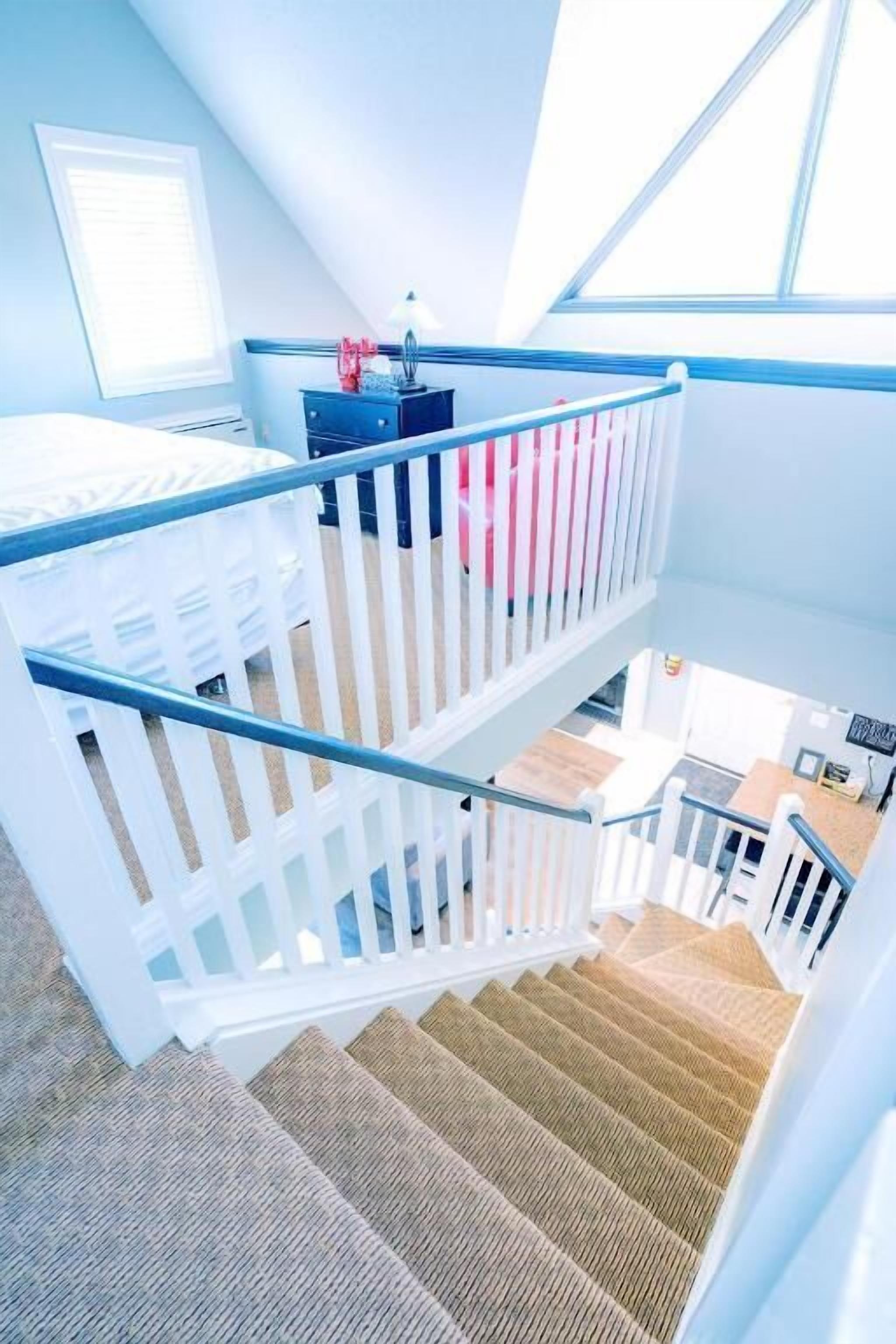 A staircase with white railings leading to a second floor.
