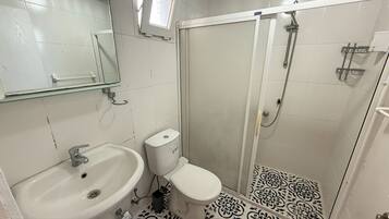 Un baño con lavamanos, inodoro y ducha.