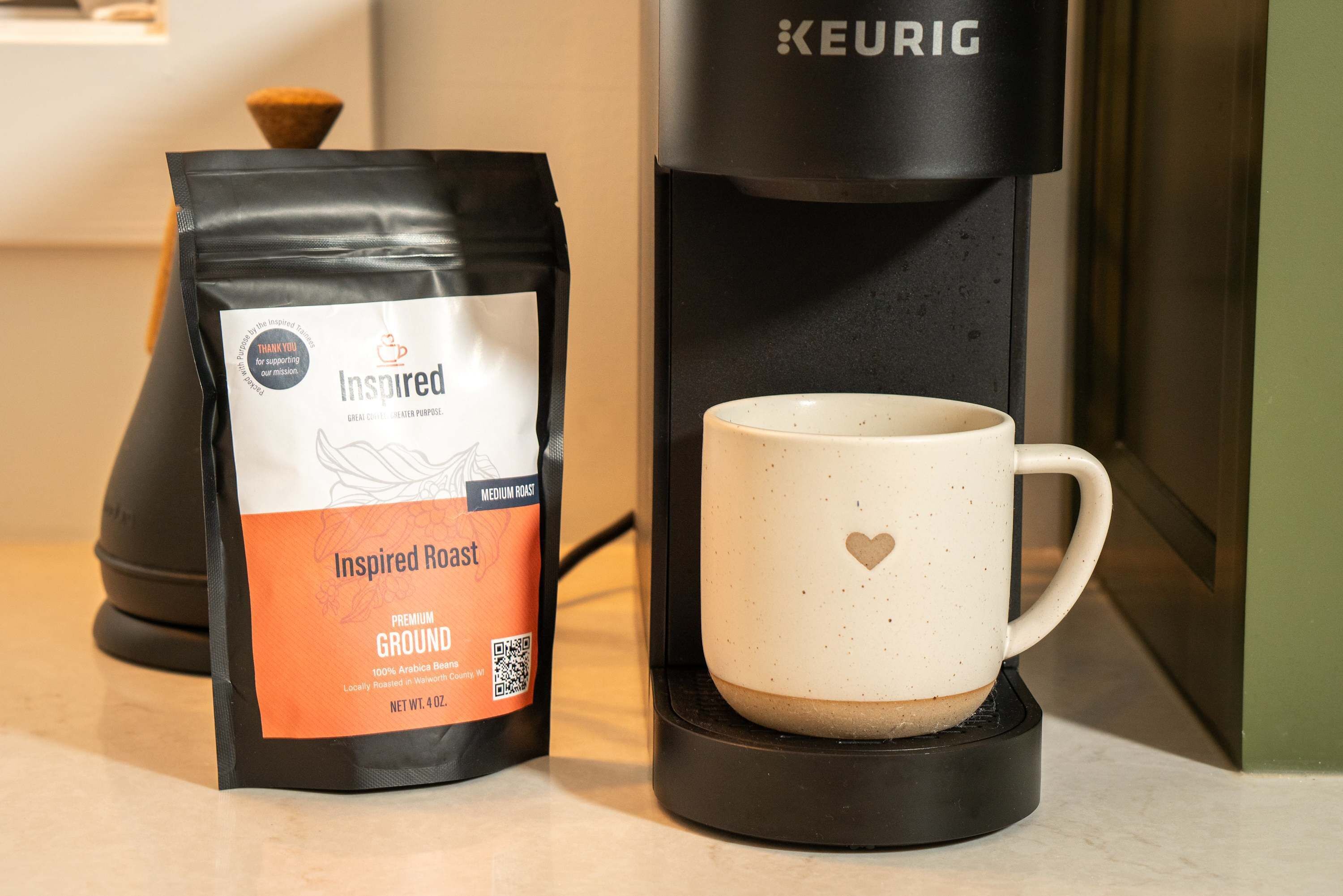 A coffee maker and a bag of Inspired Roast coffee on a kitchen counter.