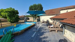 Una piscina amb tobogan, gandules i una zona coberta amb una ombrel·la.