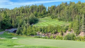 Un parcours de golf avec un pont, des arbres et un ciel dégagé.