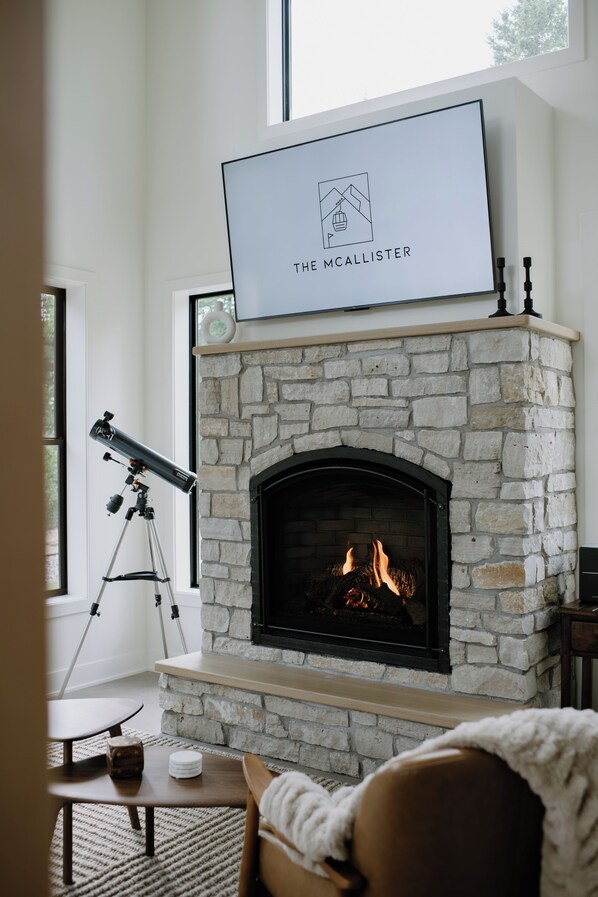 A stone fireplace with a television above it displaying "THE MCALLISTER" logo. - Ski/Golf/Trails/Winery - Putting Green - Sauna - Foosball - Sleeps 10 (Tofte)