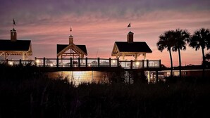 A waterfront property with a wooden bridge connecting two buildings, each with a small pavilion. - Pirate-Themed Luxury Beach House-Free Golf Cart-Ocean Views-Ocean Lakes (Myrtle Beach)