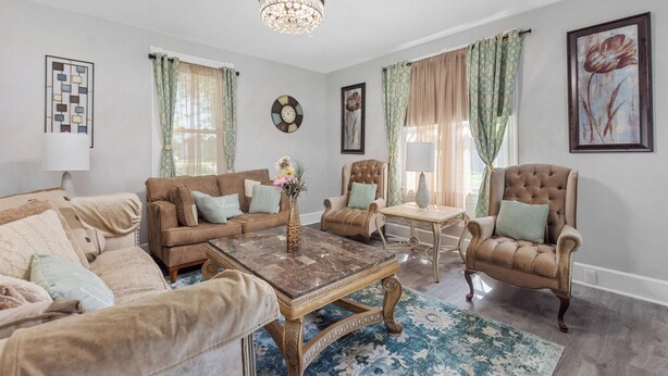 A living room with a sofa set, a coffee table, a chair, and a chandelier.