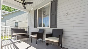 A covered porch with wicker furniture and a ceiling fan.