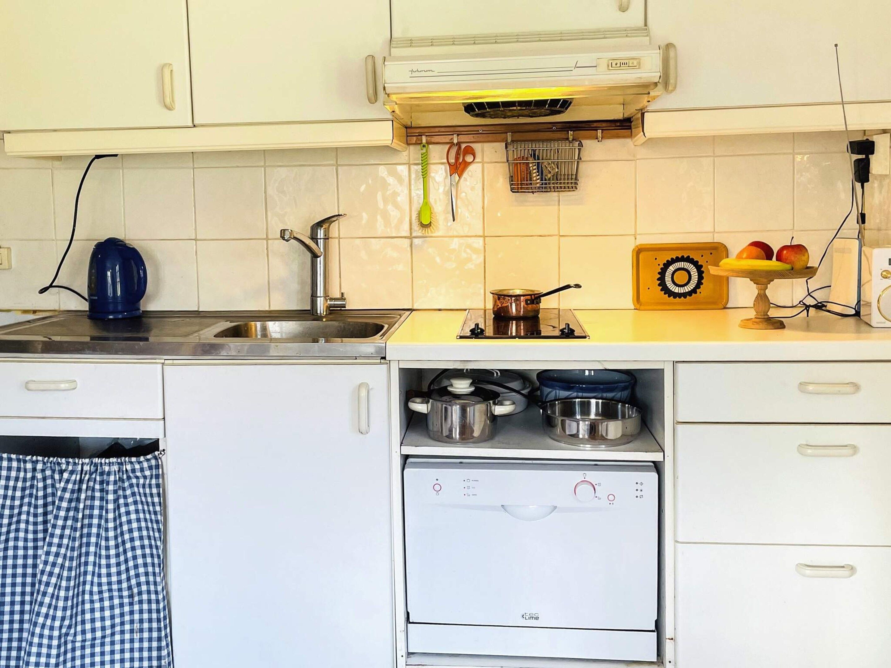 Une cuisine équipée d’un évier, d’une cuisinière et de placards.