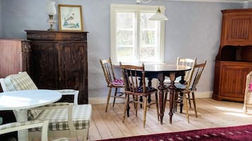 Un comedor con una mesa redonda, sillas, un ventanal y un aparador de madera.