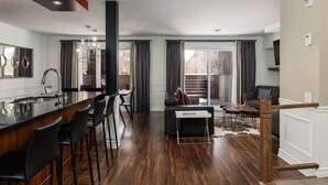 Une cuisine moderne dotée d’un îlot central, d’un coin bar et d’un espace repas comprenant un canapé et une table basse.