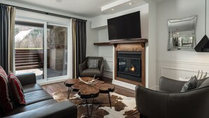 Un salon moderne avec une cheminée, des canapés en cuir, une table basse et une grande fenêtre avec des rideaux.