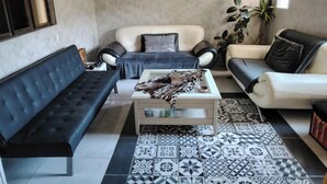 Un salon avec un canapé, une table basse et un tapis à motifs.