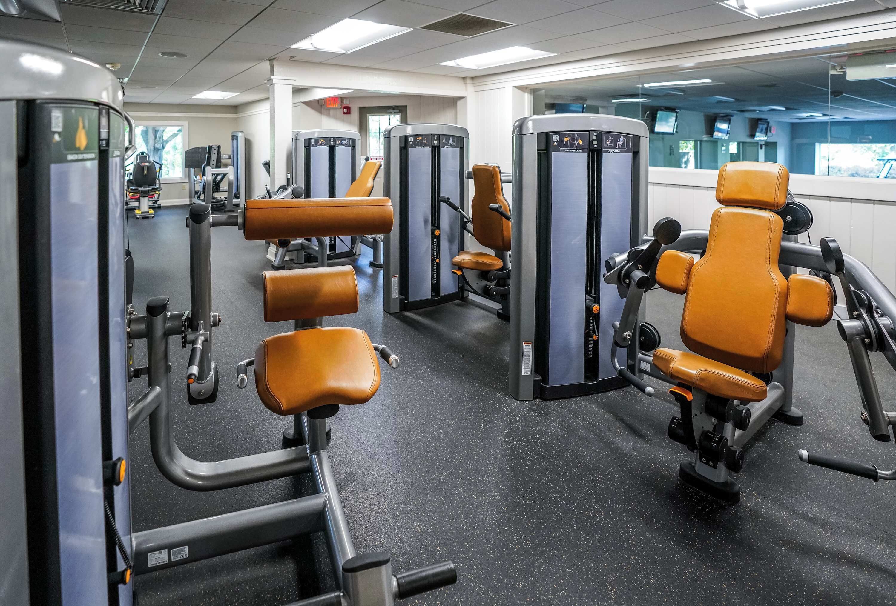 A gym with exercise equipment and leather chairs.