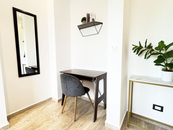 A small, modern room with a desk, chair, and a potted plant.