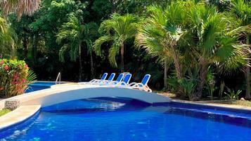 A swimming pool with lounge chairs and tropical vegetation.