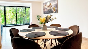 A modern dining area with a round table, black chairs, and a vase of flowers. - Modern Condo Jungle Retreat (Puerto Aventuras)
