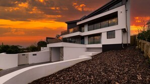 Una casa moderna de dos pisos con techo plano, ventanas amplias y entrada con rampa.