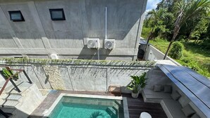 A rooftop pool with a wooden deck, a seating area with cushions, and a view of the surrounding greenery. - 3-bedroom villa in fabulous Uluwatu Bali with pool (Bali)