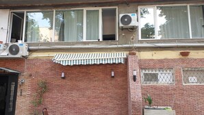 A brick building with a balcony, air conditioning units, a striped awning, and outdoor seating. - Hotel Nino on Tsamebuli (Tbilisi)