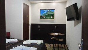 A hotel room with a bed, a small table with chairs, a painting on the wall, and a TV mounted on the wall. - Hotel Nino on Tsamebuli (Tbilisi)