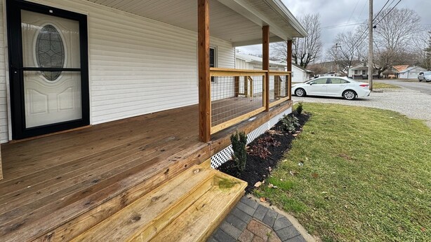 A house with a covered porch, a front door with a glass panel, and a driveway with a parked car. - Quaint Village 4 bedroom home in Friendship IN (Versailles)
