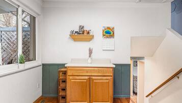A kitchen with a wooden cabinet, a small potted plant, and a calendar on the wall.