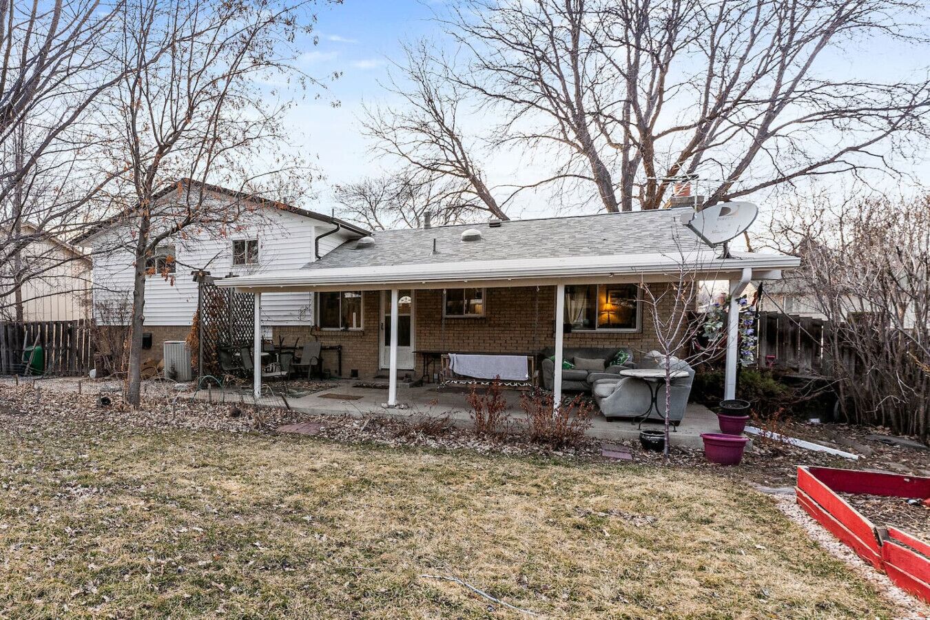A single-story house with a covered patio, a brick exterior, and a satellite dish.