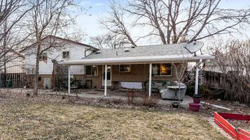 A single-story house with a covered patio, a brick exterior, and a satellite dish.