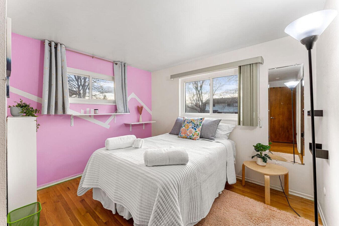 A bedroom with a bed, a nightstand, a lamp, a window, and a door.