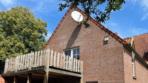 Een bakstenen gebouw met een houten balkon en een schotelantenne.