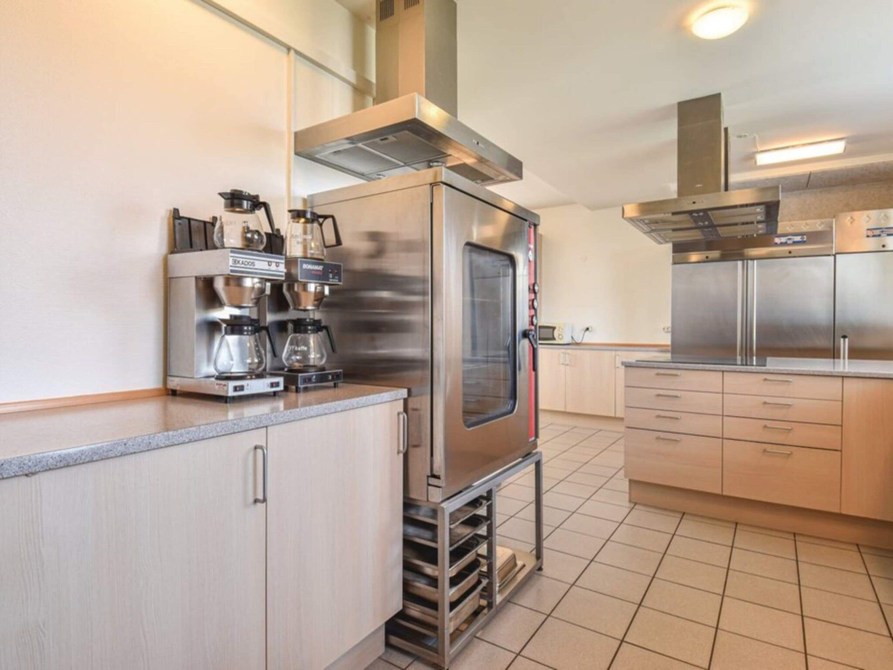 Een moderne keuken met roestvrijstalen apparatuur, een koffieapparaat en een ingebouwde oven.