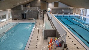 Ein Hallenbad mit mehreren Bahnen, einer Treppe und einem Rettungsschwimmerstand.