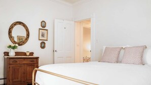 A bedroom with a bed, dresser, and a door leading to another room. - Farmhouse With Heated Pool on Almost 160 Acres! (Elkhorn)