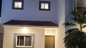 Un bâtiment à deux étages, doté d’une façade bleue, d’un toit en tuiles et d’un petit porche à l’avant.