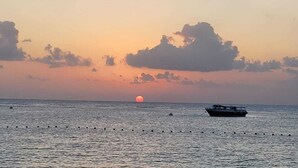 Un bateau sur une eau calme, avec un coucher de soleil en arrière-plan.