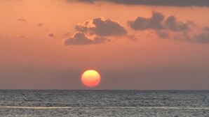 Un coucher de soleil sur l’océan, avec des nuages dans le ciel.